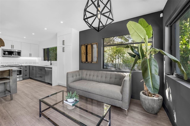 living room with sink, light wood-type flooring, and a wealth of natural light