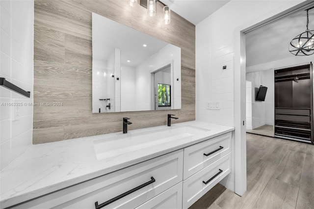 bathroom featuring vanity, wood-type flooring, and tile walls