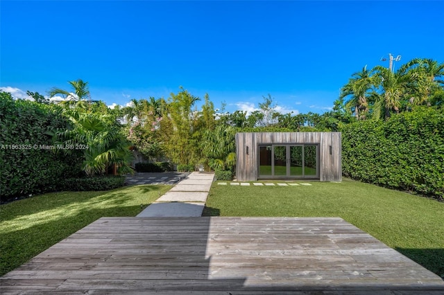 view of property's community featuring a deck, an outdoor structure, and a lawn