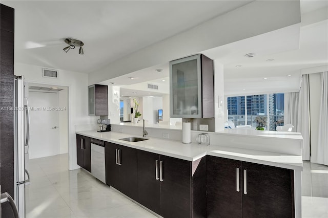 kitchen with dark brown cabinets, kitchen peninsula, appliances with stainless steel finishes, and sink