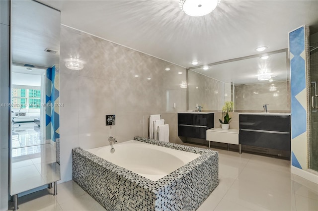 bathroom with vanity, a relaxing tiled tub, tile walls, and tile patterned flooring