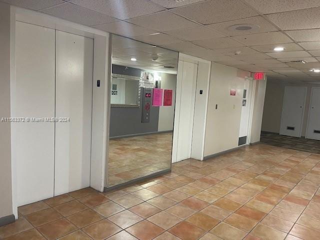 tiled spare room with a paneled ceiling and elevator