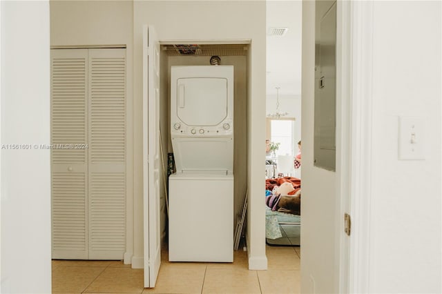 washroom with light tile floors and stacked washer and clothes dryer