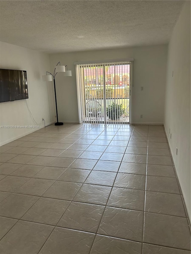 unfurnished room featuring a textured ceiling and tile floors