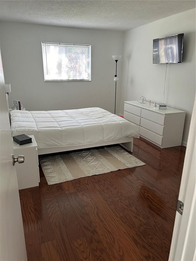 bedroom featuring a textured ceiling and dark wood-type flooring