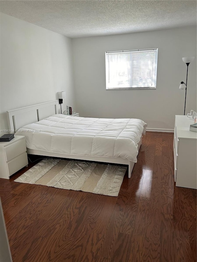 bedroom with a textured ceiling and dark hardwood / wood-style floors