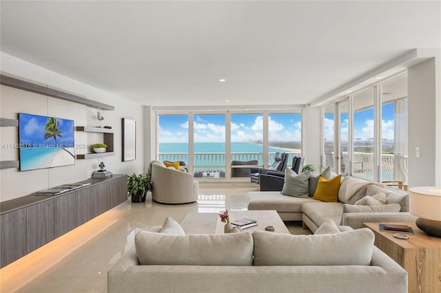 living room featuring a healthy amount of sunlight, expansive windows, light tile flooring, and a water view