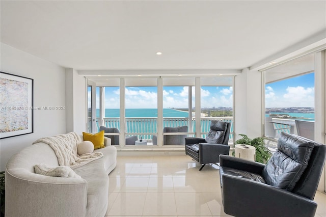 living room with expansive windows, light tile floors, and a water view