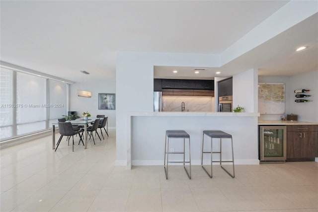 kitchen with a breakfast bar, light tile flooring, wine cooler, appliances with stainless steel finishes, and hanging light fixtures