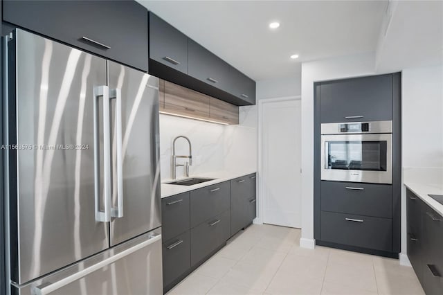 kitchen with light tile floors, sink, tasteful backsplash, stainless steel appliances, and gray cabinetry