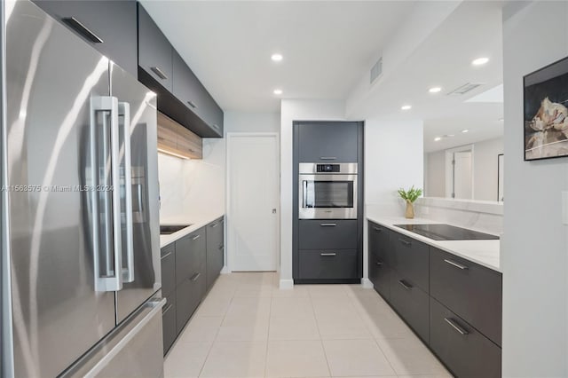 kitchen featuring light stone counters, gray cabinetry, stainless steel appliances, and light tile floors