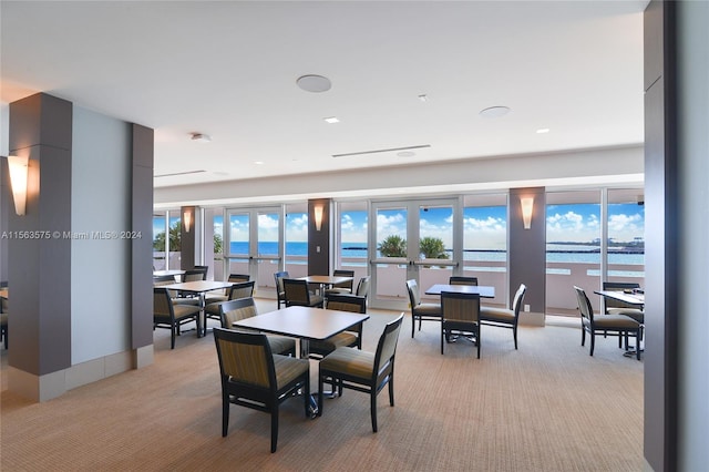 dining room featuring a water view, light carpet, and french doors