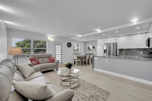 living room featuring recessed lighting, a healthy amount of sunlight, a textured ceiling, and baseboards