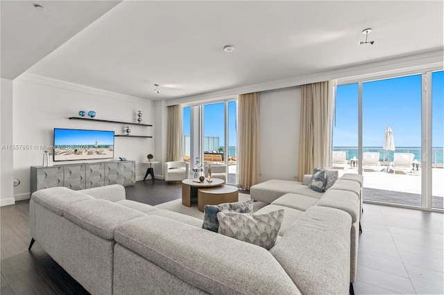 tiled living room featuring a water view, crown molding, and a view of the beach