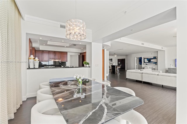 living room with a raised ceiling, dark hardwood / wood-style flooring, and a notable chandelier