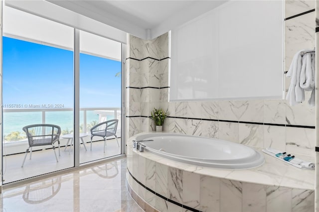 bathroom featuring a healthy amount of sunlight, tile flooring, tiled bath, and a water view