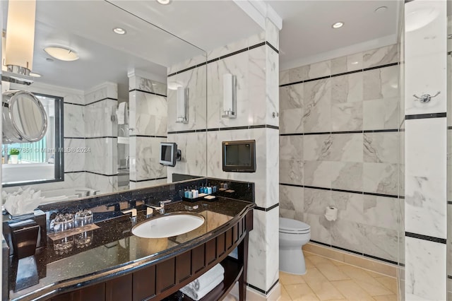 bathroom featuring tile walls, a shower with shower door, toilet, vanity, and tile floors