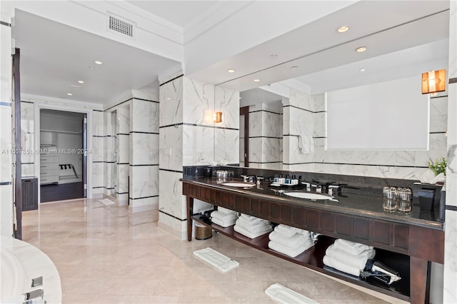 bathroom with vanity with extensive cabinet space, double sink, tile floors, and tile walls