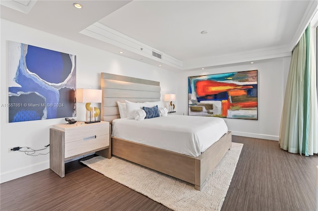 bedroom with dark wood-type flooring and a raised ceiling