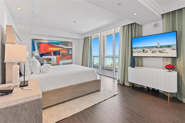 bedroom featuring a raised ceiling, expansive windows, access to exterior, and a water view