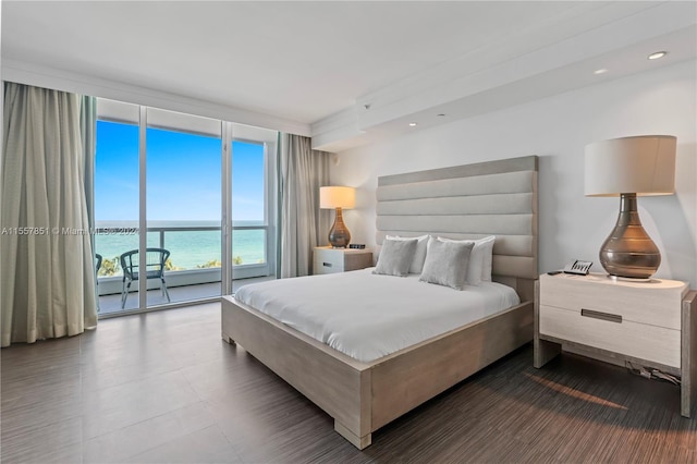 bedroom featuring a wall of windows, access to exterior, and a water view