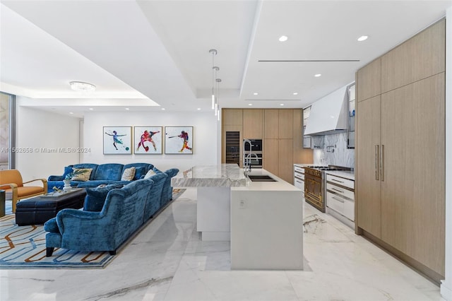 kitchen featuring backsplash, a center island with sink, sink, light tile flooring, and custom range hood