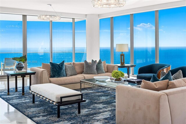 living room featuring a chandelier, floor to ceiling windows, a water view, and a healthy amount of sunlight