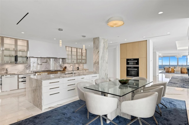 kitchen featuring a center island, white cabinets, black double oven, backsplash, and decorative light fixtures