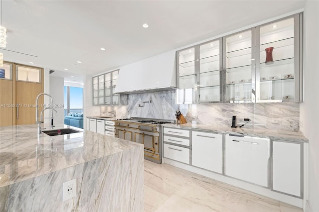 kitchen featuring premium range hood, light stone counters, backsplash, sink, and white cabinets