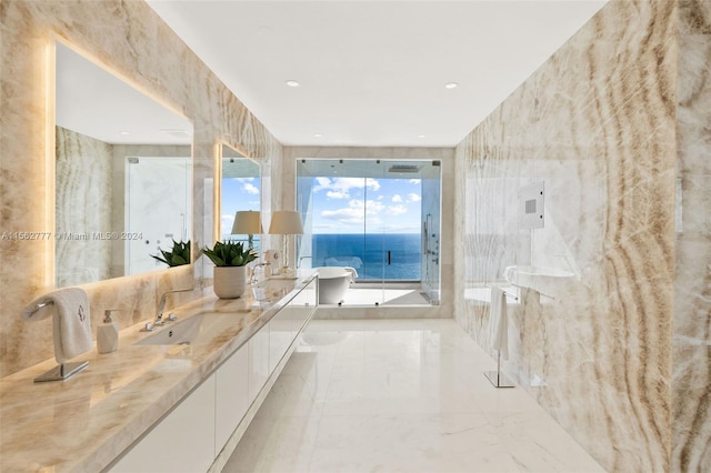 bathroom with tile walls, vanity, a water view, and a bathtub