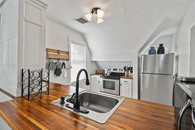 kitchen with butcher block counters, hardwood / wood-style floors, stainless steel appliances, sink, and white cabinetry