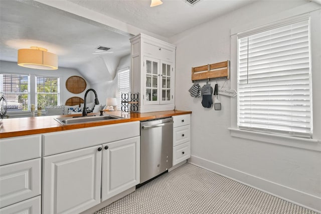 kitchen featuring stainless steel dishwasher, sink, light tile floors, and white cabinets