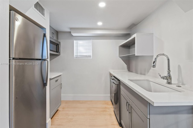 kitchen featuring appliances with stainless steel finishes, sink, light wood-type flooring, and gray cabinets