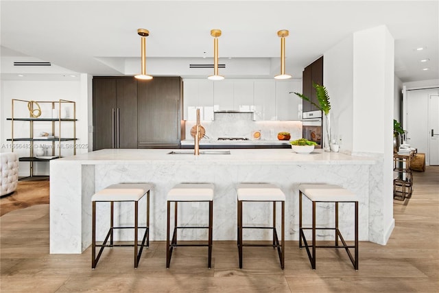 kitchen featuring tasteful backsplash, hanging light fixtures, a kitchen breakfast bar, and modern cabinets