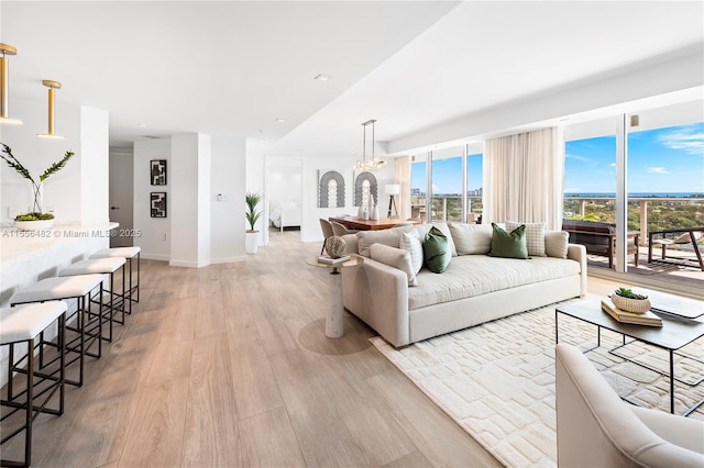 living room with baseboards, a notable chandelier, and light wood finished floors