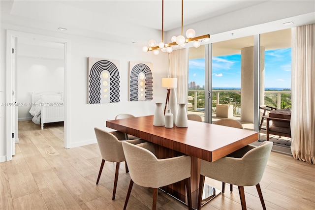 dining area featuring an inviting chandelier, light wood-style flooring, and baseboards