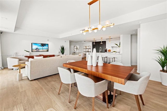 dining area featuring baseboards, recessed lighting, a raised ceiling, and light wood-style floors