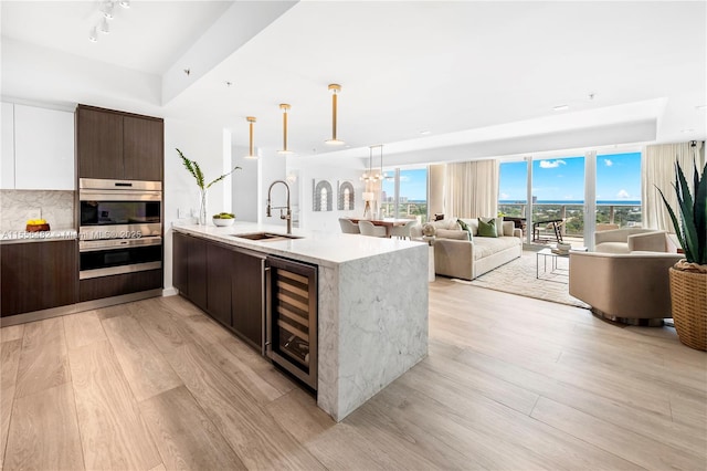 kitchen with beverage cooler, modern cabinets, open floor plan, dark brown cabinets, and a sink