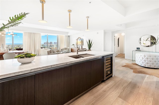 kitchen featuring beverage cooler, dark brown cabinetry, a sink, and open floor plan