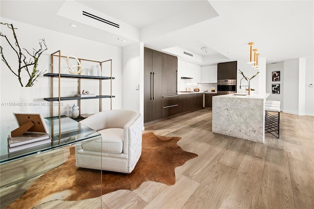 interior space with a tray ceiling, baseboards, light wood finished floors, and recessed lighting