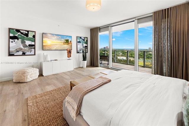 bedroom with a wall of windows, access to exterior, baseboards, and wood finished floors