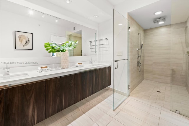 bathroom with double vanity, a stall shower, visible vents, and a sink