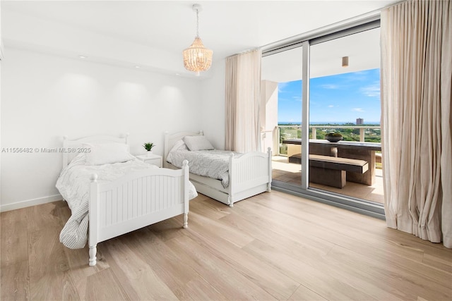 bedroom featuring baseboards, access to outside, expansive windows, light wood-type flooring, and a chandelier