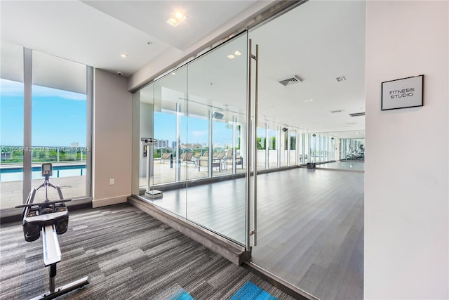 exercise room with expansive windows, visible vents, and baseboards