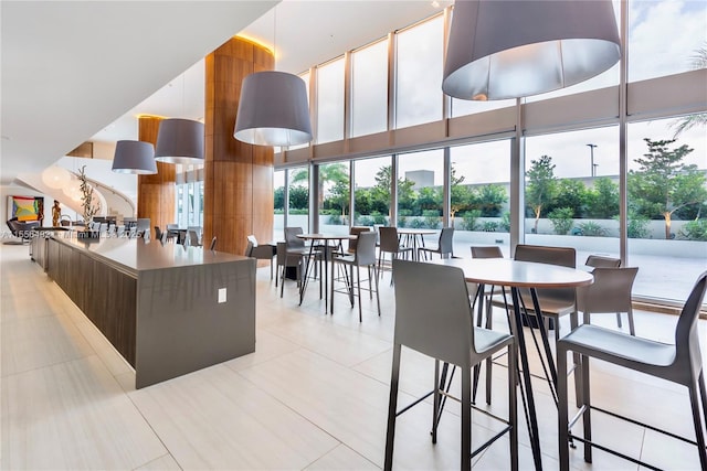 interior space with a towering ceiling, light tile patterned floors, expansive windows, and modern cabinets