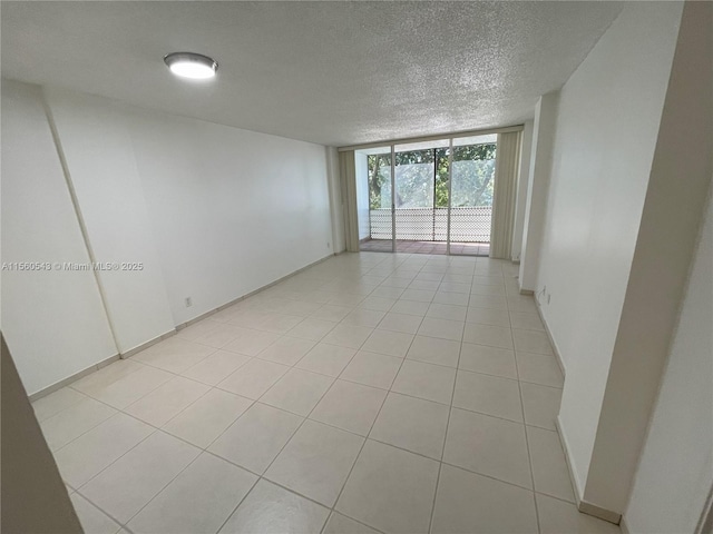 empty room featuring floor to ceiling windows, light tile patterned floors, and a textured ceiling