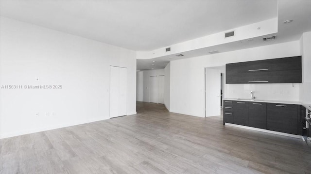 unfurnished living room with sink and light hardwood / wood-style floors