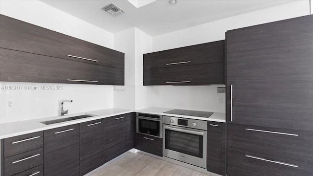 kitchen featuring extractor fan, sink, appliances with stainless steel finishes, and light hardwood / wood-style flooring