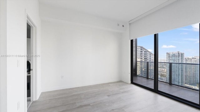 unfurnished room featuring floor to ceiling windows and light hardwood / wood-style floors