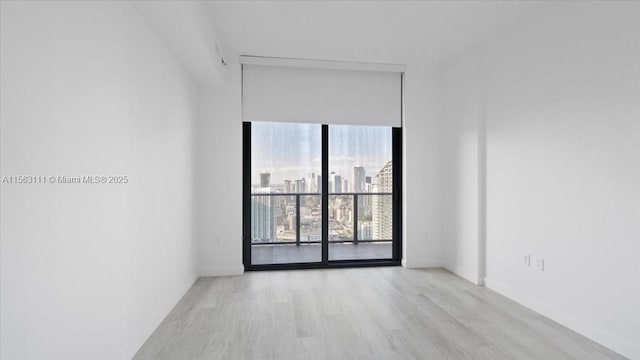 unfurnished room with light hardwood / wood-style floors and a wall of windows